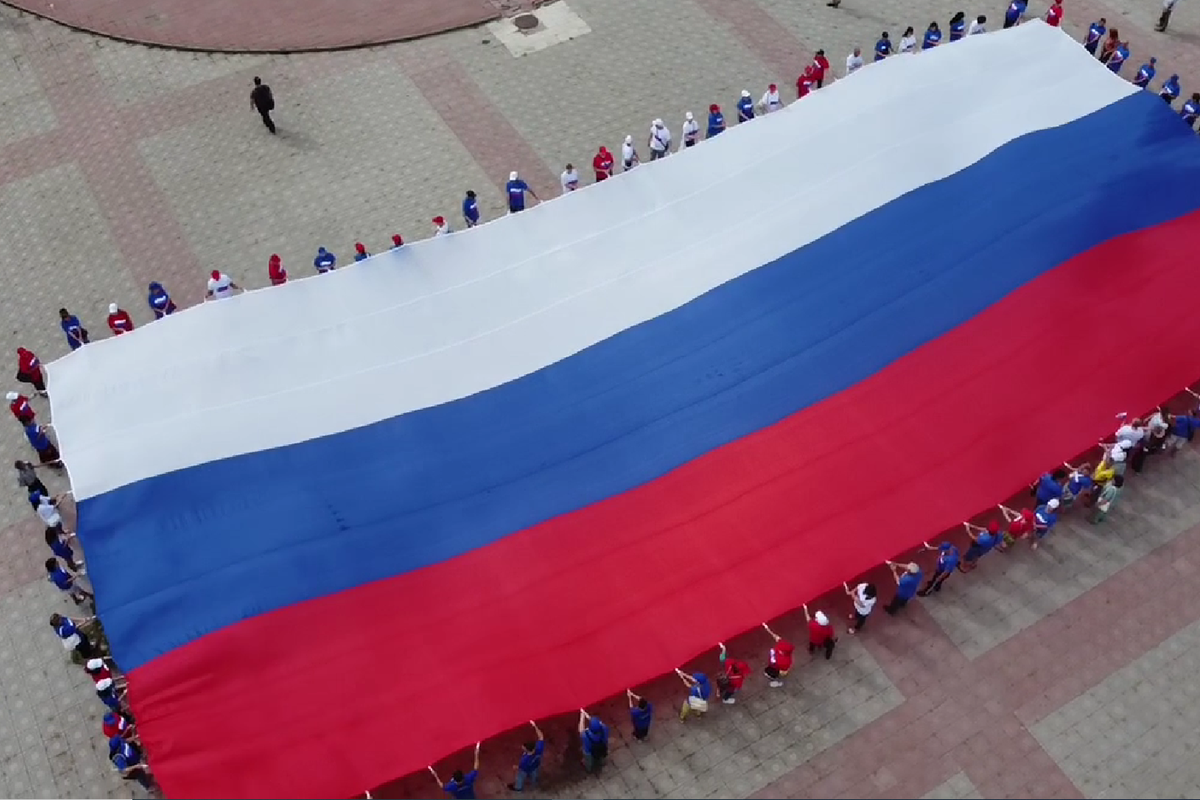 В ЛНР (террористическая организация на территории Луганской области Украины) активисты растянули российский (страна-террорист) флаг размером с Дом молодежи